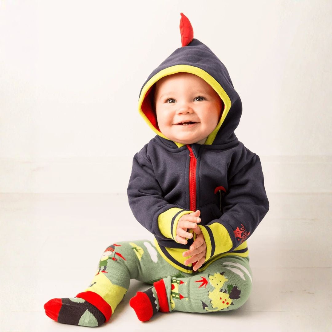 Baby wearing a colorful dinosaur-themed outfit with a hood on a white background