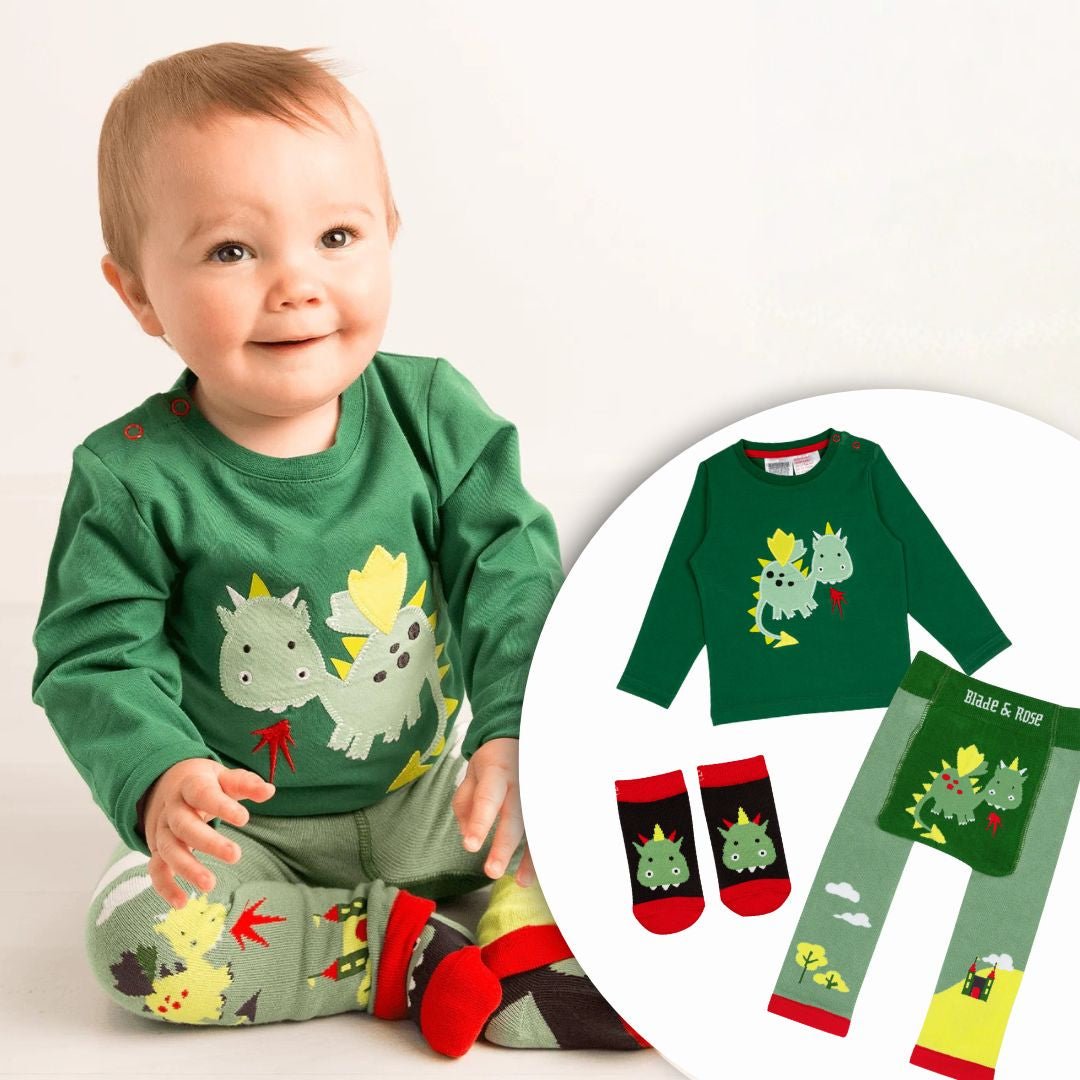 Baby wearing a green dinosaur-themed outfit with matching socks, on a plain background.