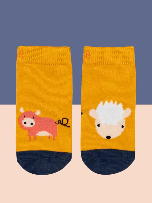 Two yellow socks with animal illustrations on a blue and pink gradient background