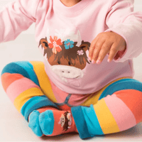 Baby wearing a pink outfit with a cartoon design and colorful socks on a white background