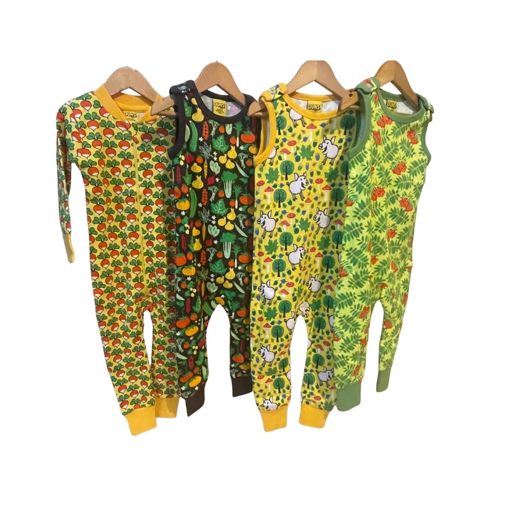Four children's onesies with colorful patterns on hangers against a white background