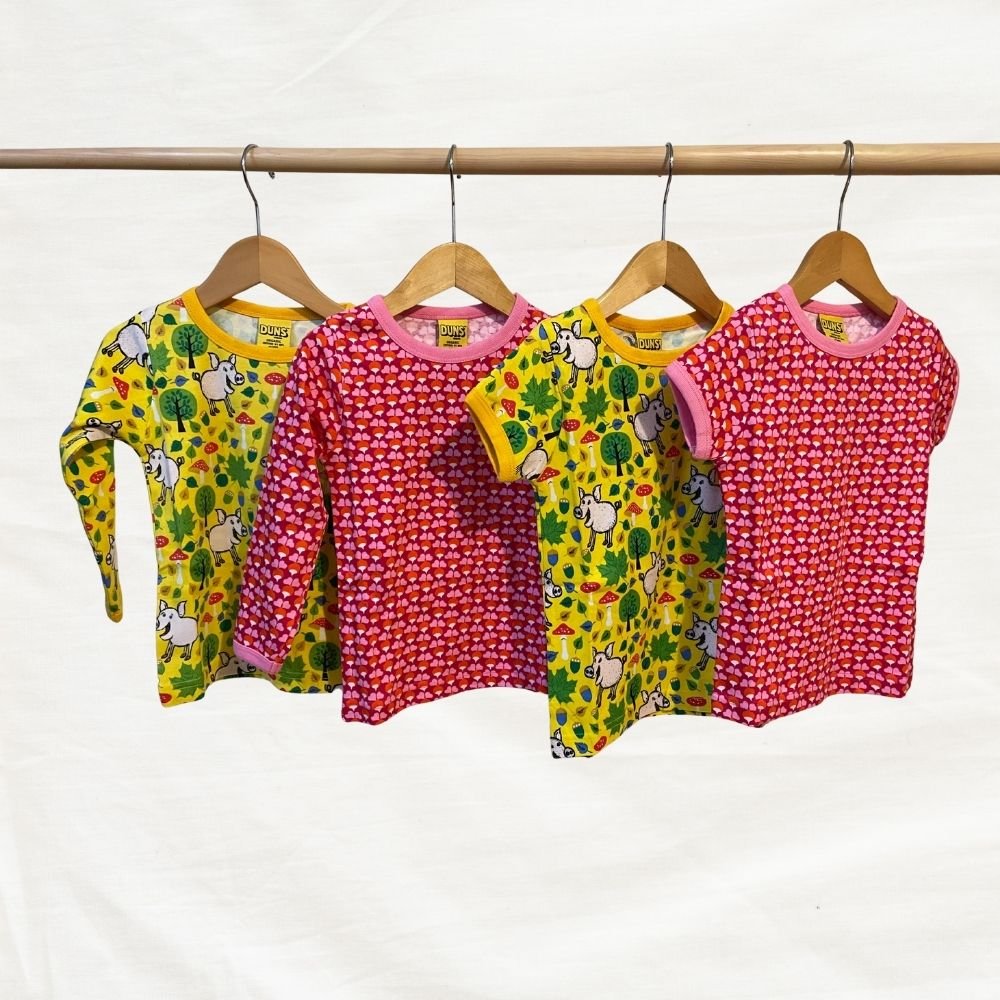 Four children's t-shirt  sets with animal patterns on hangers against a white background