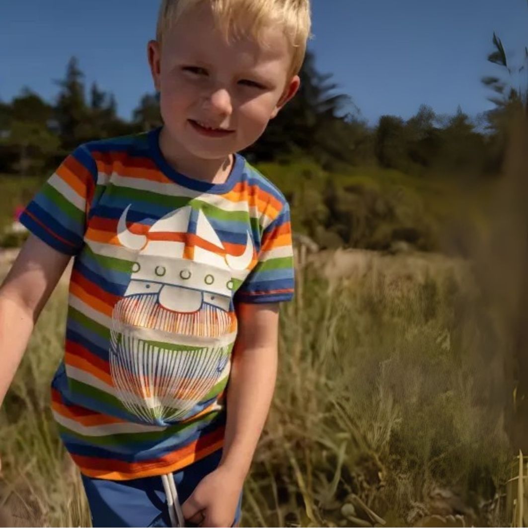 Child wearing a colorful striped shirt with a graphic design outdoors