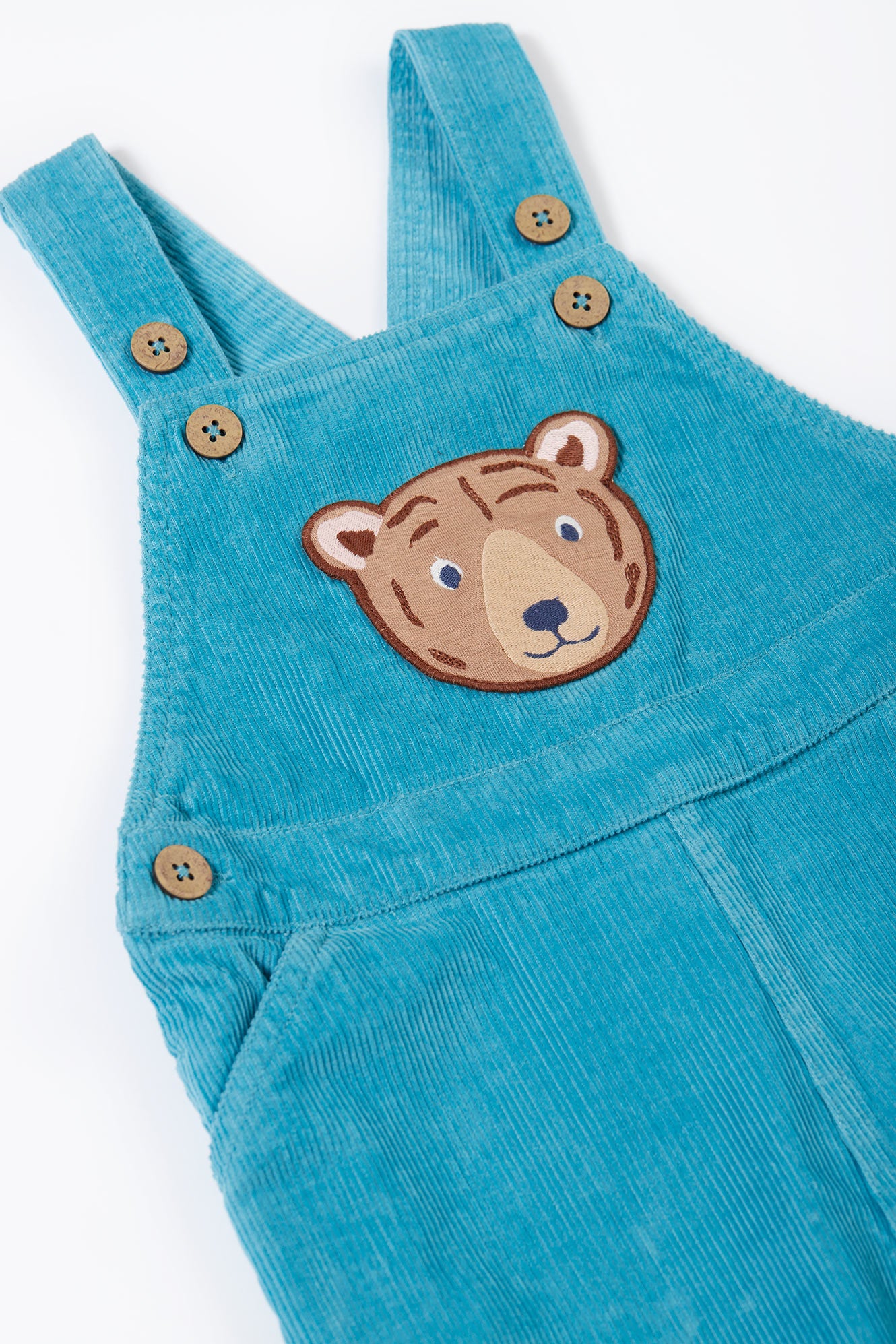 Blue corduroy overalls with a bear patch on a white background