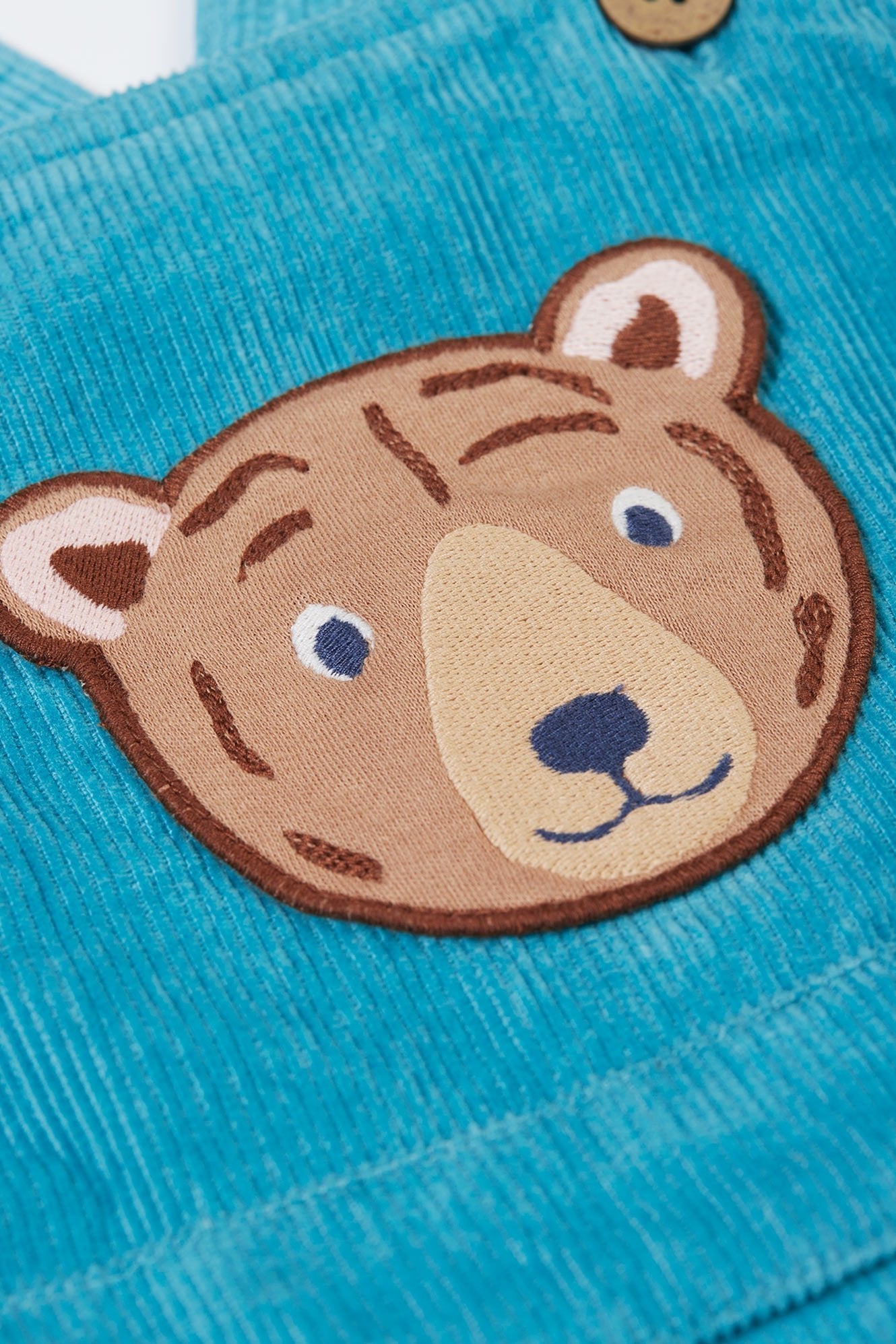 Close-up of a teddy bear face patch on blue fabric