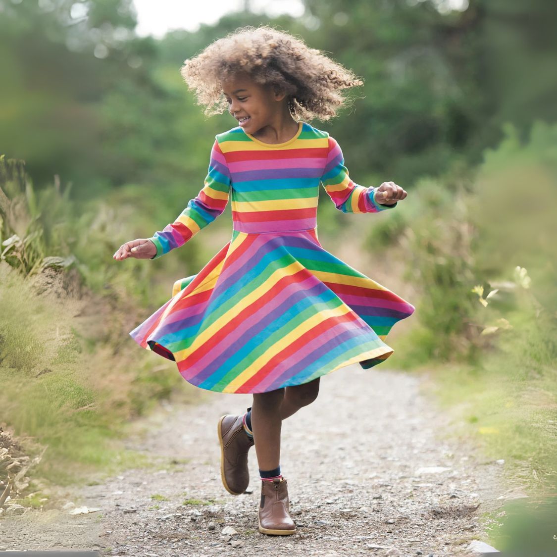 Child in a colorful rainbow dress walking on a path outdoors