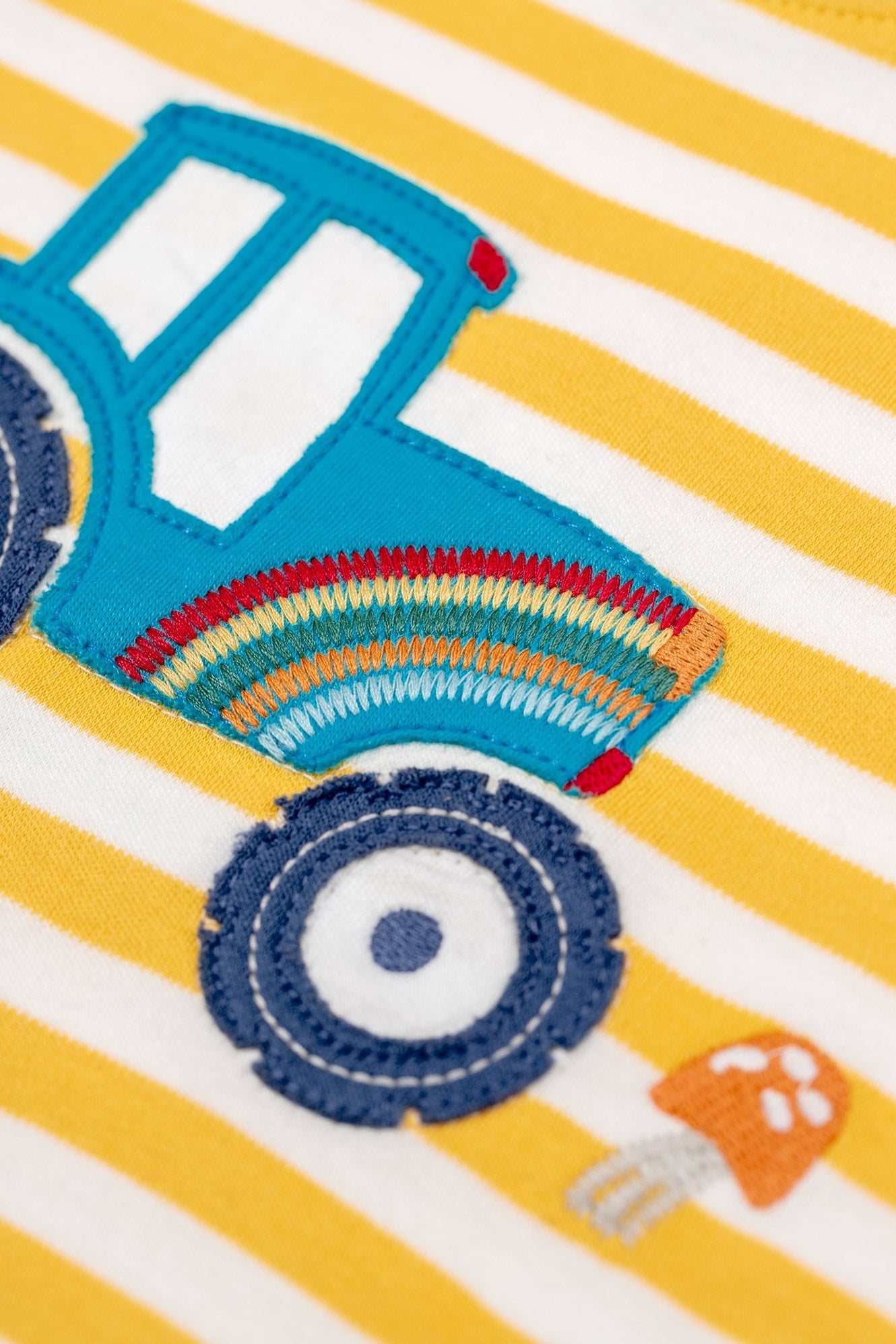 Colorful embroidered tractor design on a yellow and white striped fabric