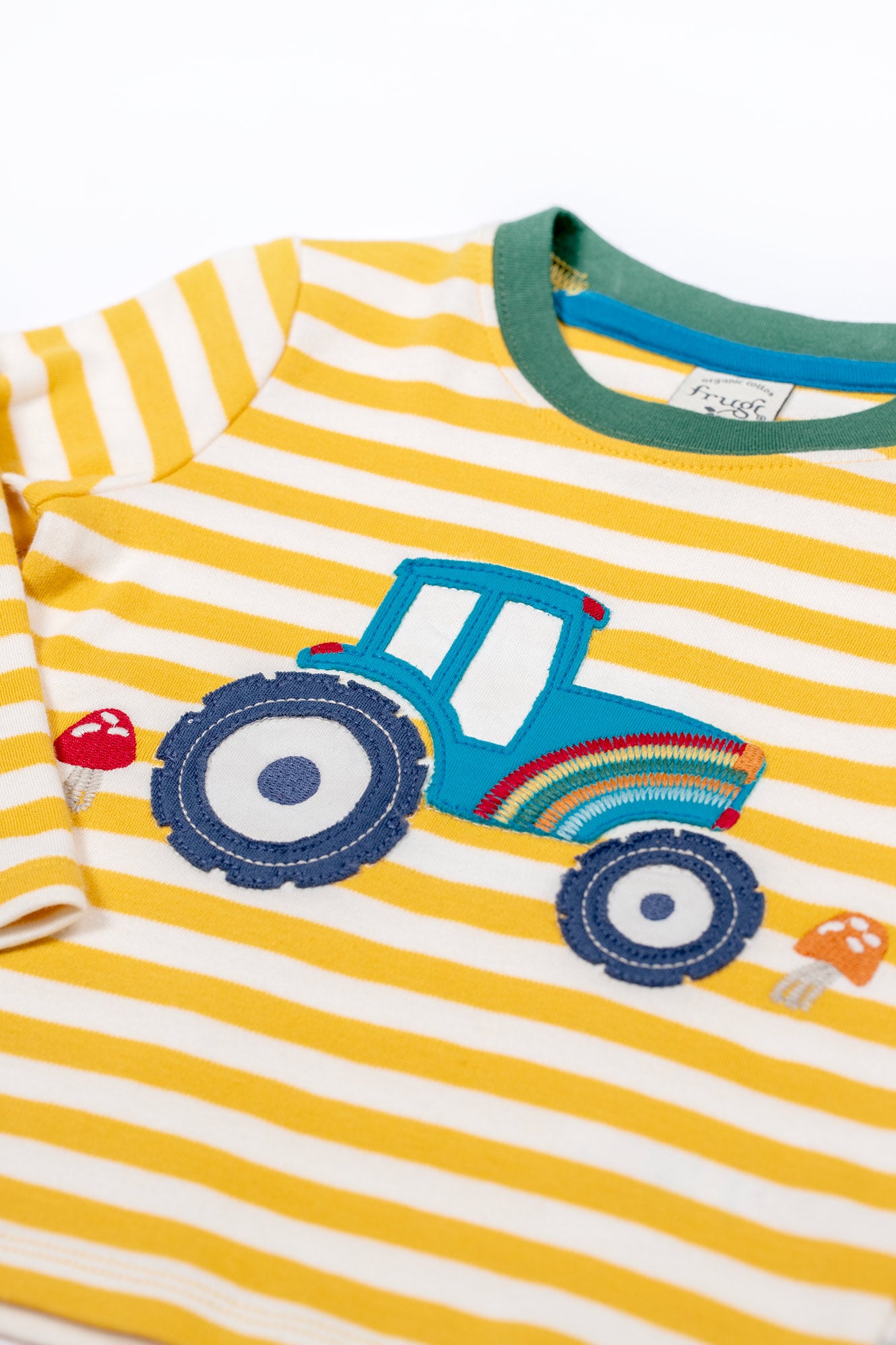 Yellow and white striped shirt with a blue tractor design on a white background