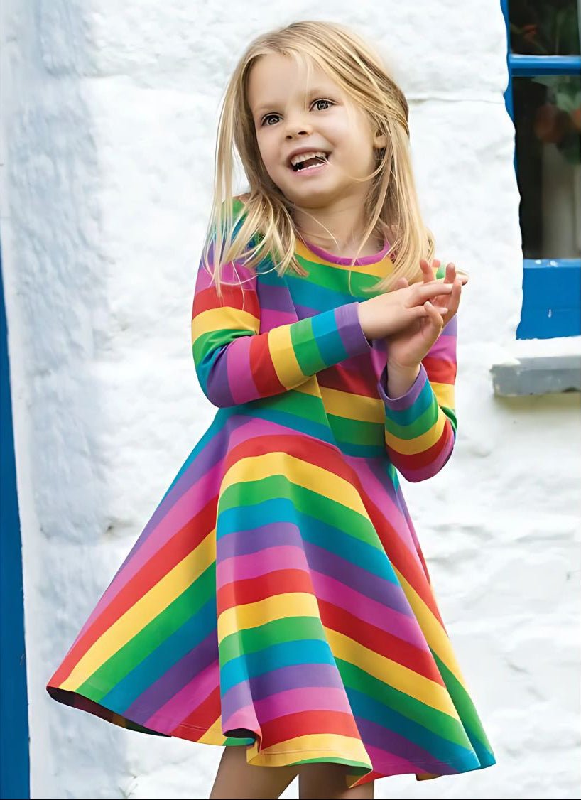 Child wearing a colorful rainbow dress standing against a white background