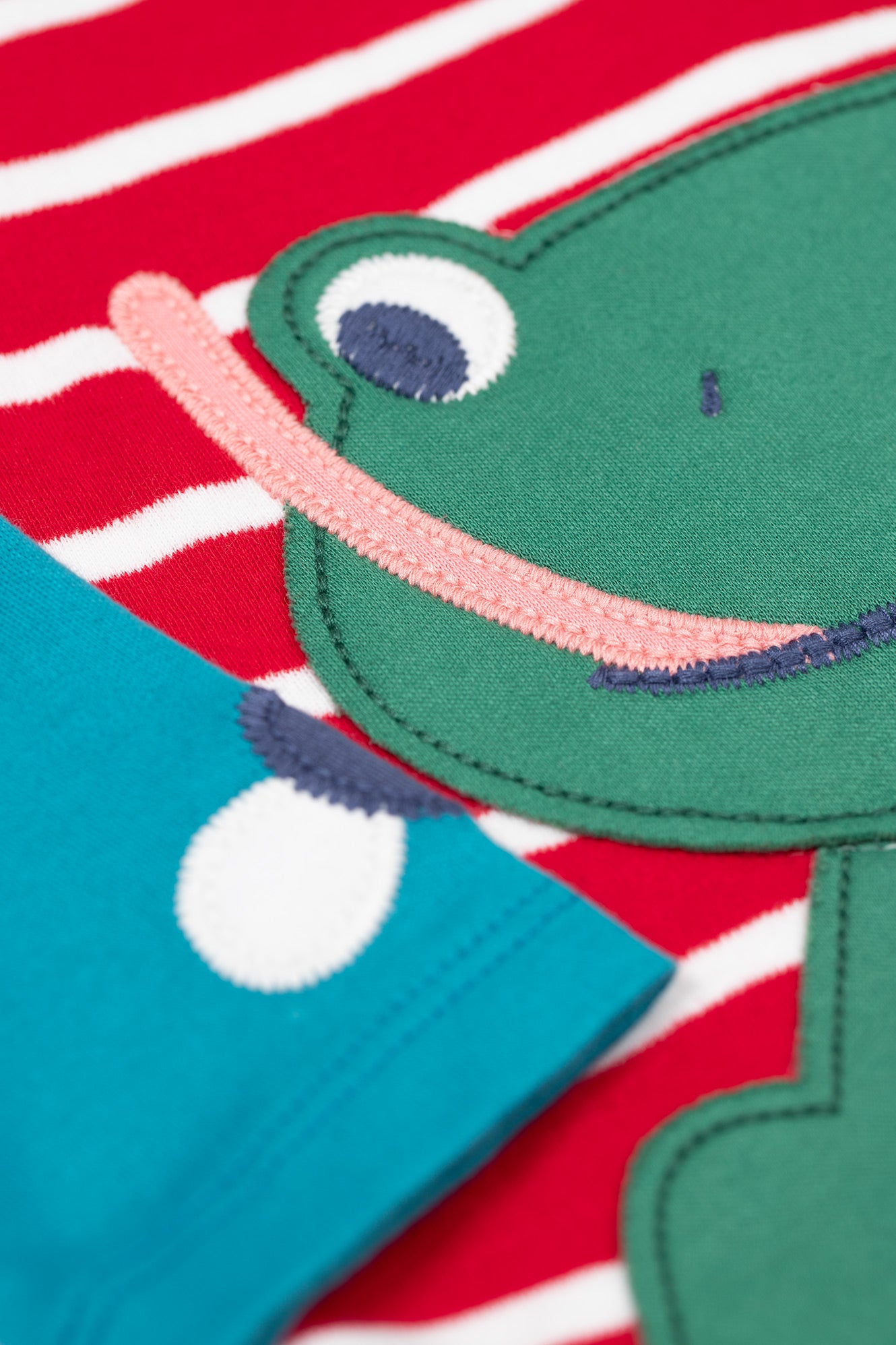 Close-up of a green fish-shaped object on a red and white striped background