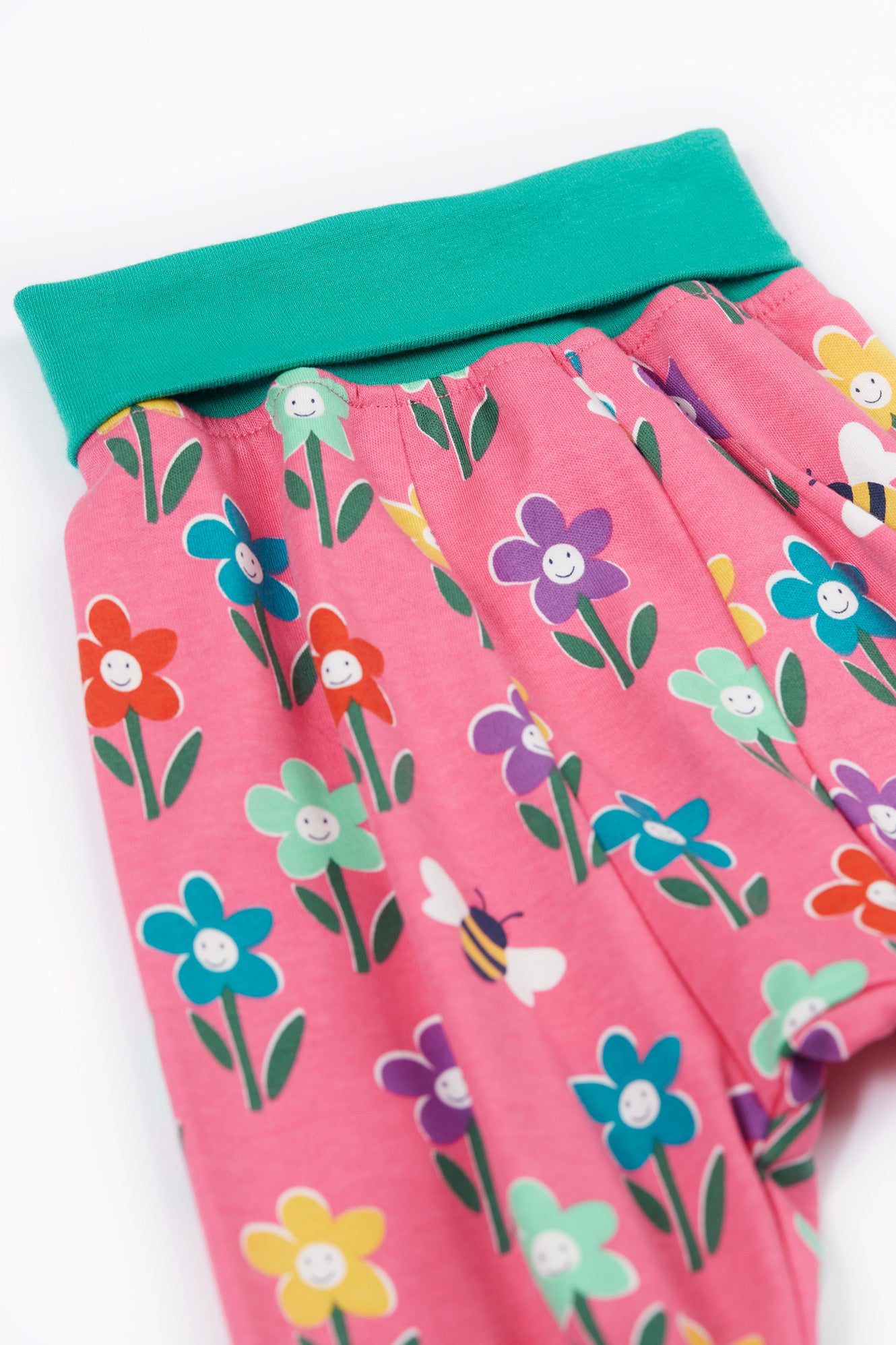 Pink shorts with floral pattern and green waistband on a white background