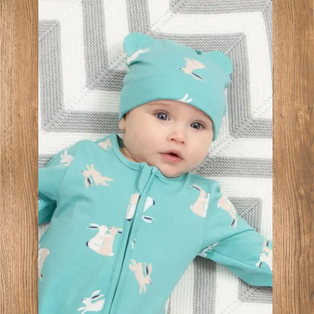 Baby wearing a matching turquoise outfit with animal patterns on a textured surface