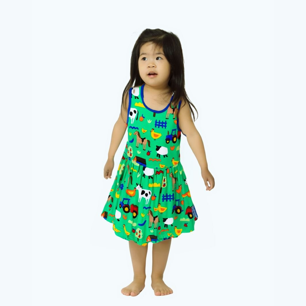 Child wearing a colorful dress with farm animal pattern on a white background