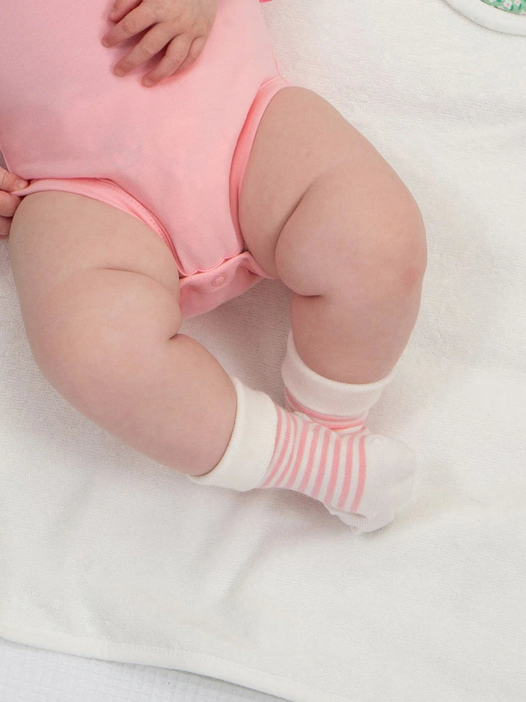 Baby wearing pink striped socks on a white background