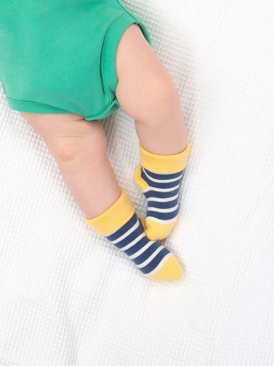 Child wearing yellow and blue striped socks on a white surface