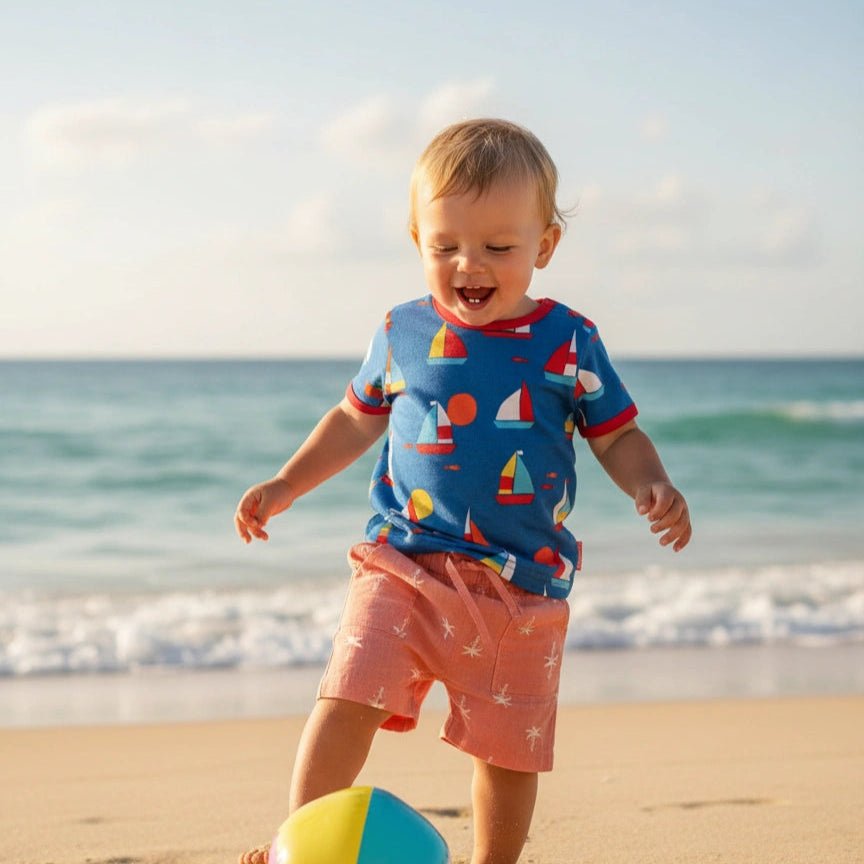 Child playing with a beach ball on a sandy beach with ocean and sky in the background
