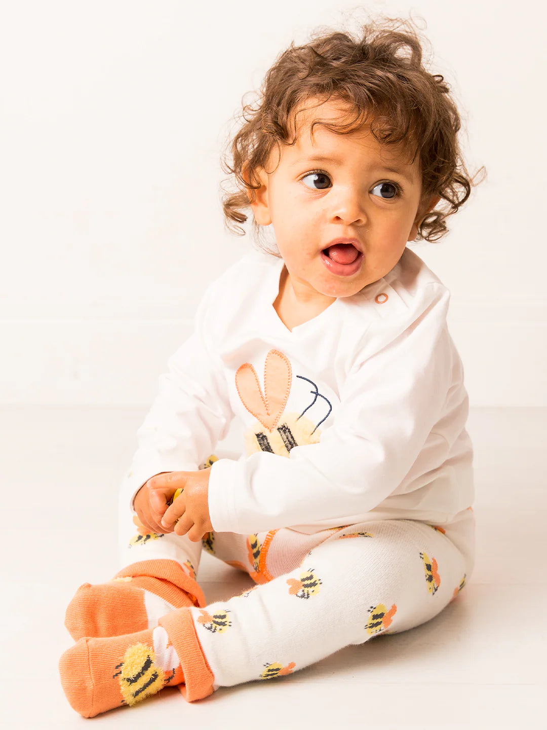 Child wearing a white onesie with bunny design on a light background