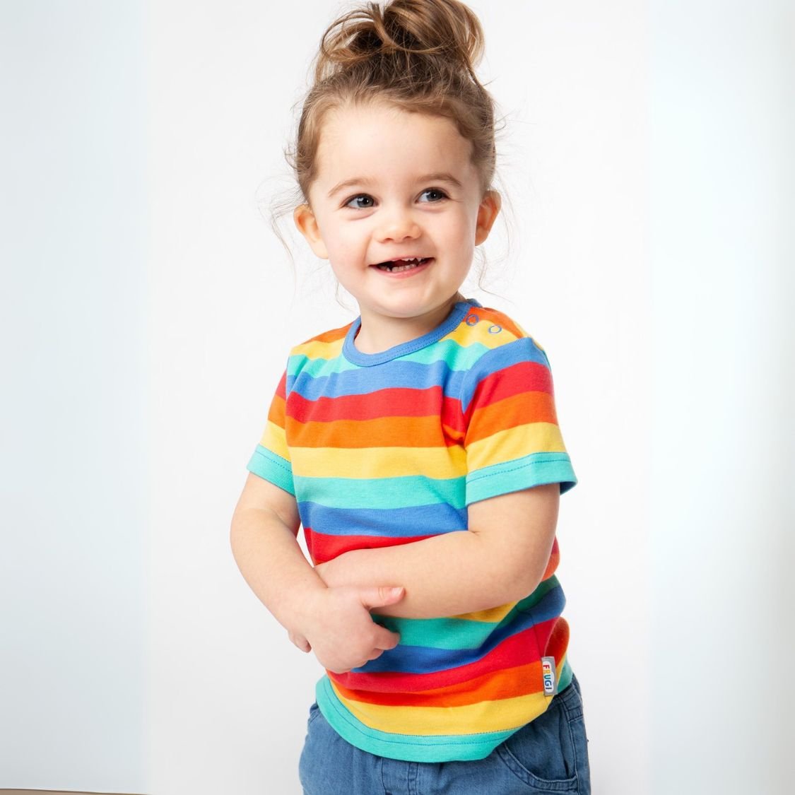 Child wearing a rainbow striped shirt on a white background