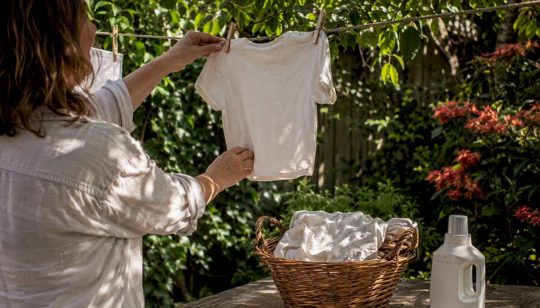 Hands hanging organic cotton baby top on line
