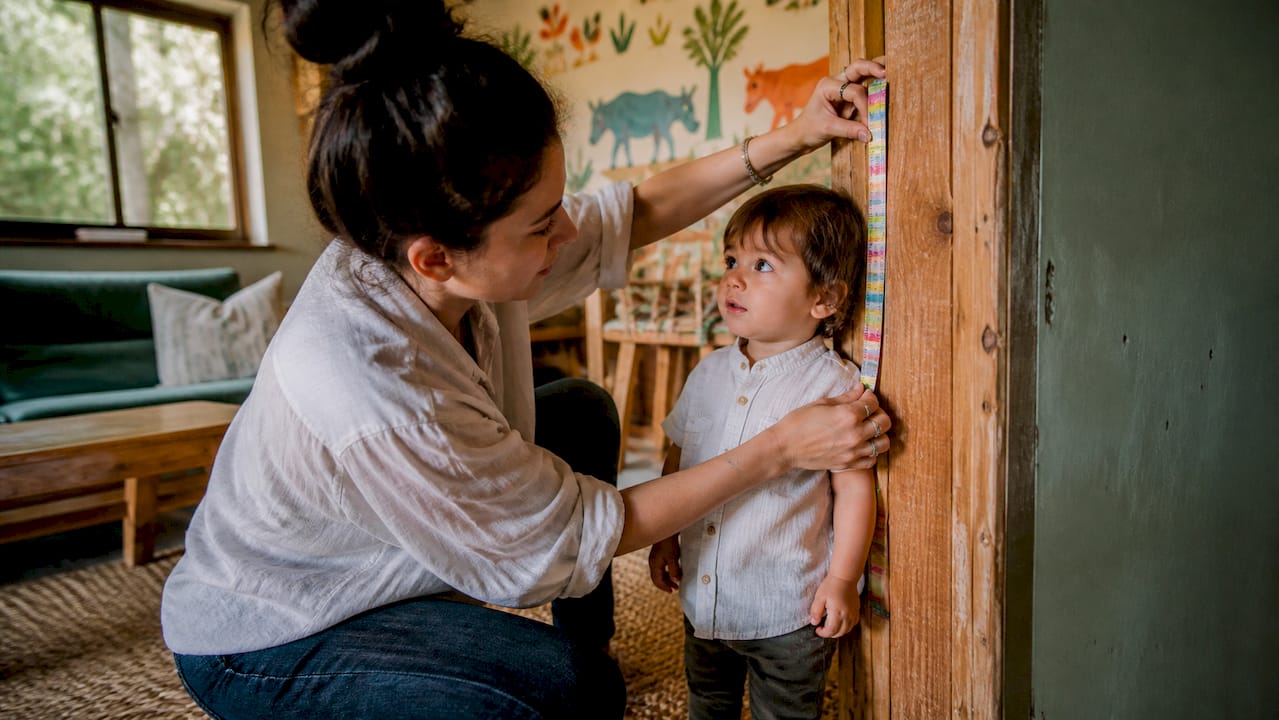 Parent measuring toddler's height at doorframe