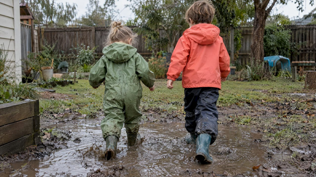 Children in two rainwear styles playing in mud