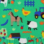 Green fabric with colorful farm animal and tractor pattern featuring horse, sheep, chickens, and barnyard elements