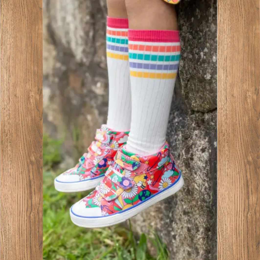 Colorful floral sneakers worn with white socks featuring rainbow stripes against a natural background.