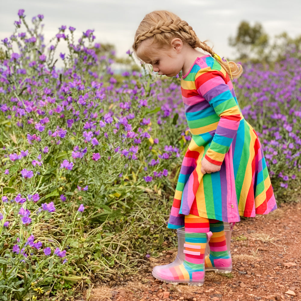 Child in a colorful striped outfit standing in a field of purple flowers