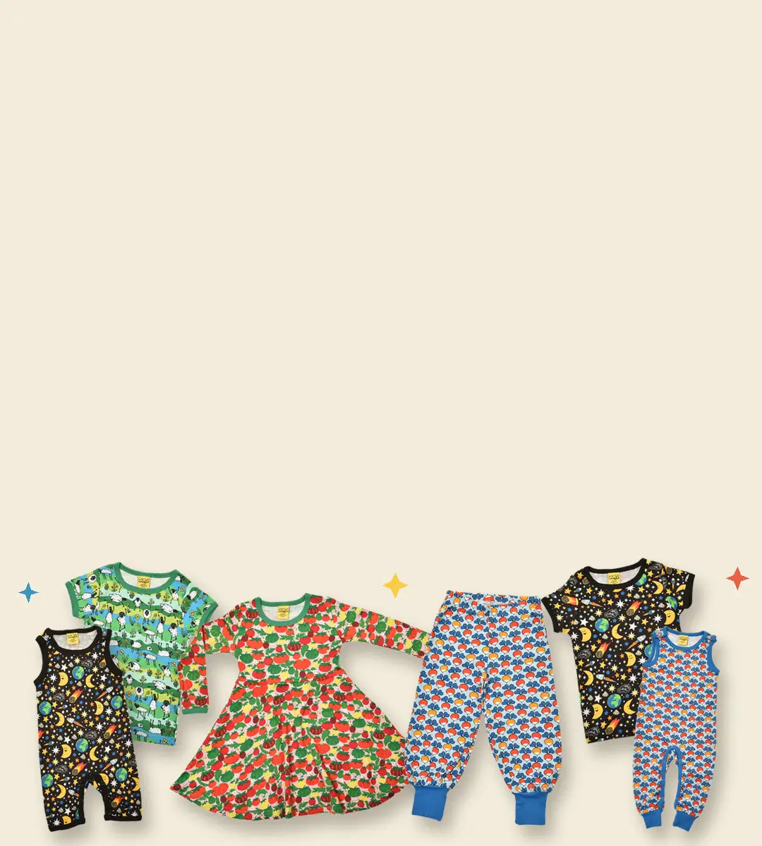 Six baby clothing sets arranged in a row on a light beige background, including black space-print outfits, green dinosaur-patterned pieces, and red strawberry-print dresses with blue patterned pants and matching sets.