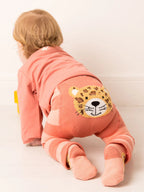 Child wearing a pink outfit with a jaguar patch on a white background