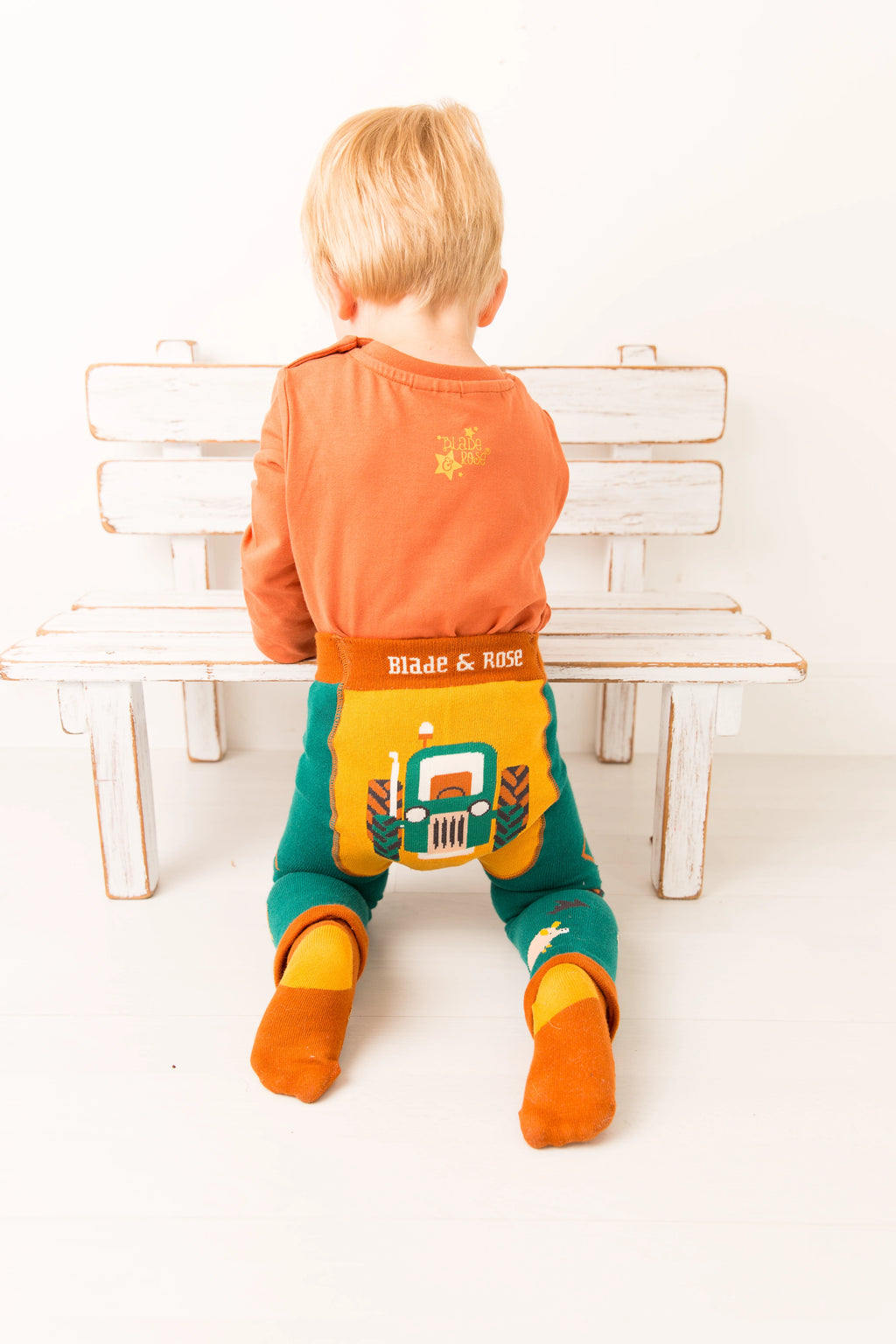 Child sitting on a bench wearing colorful clothing with visible branding.
