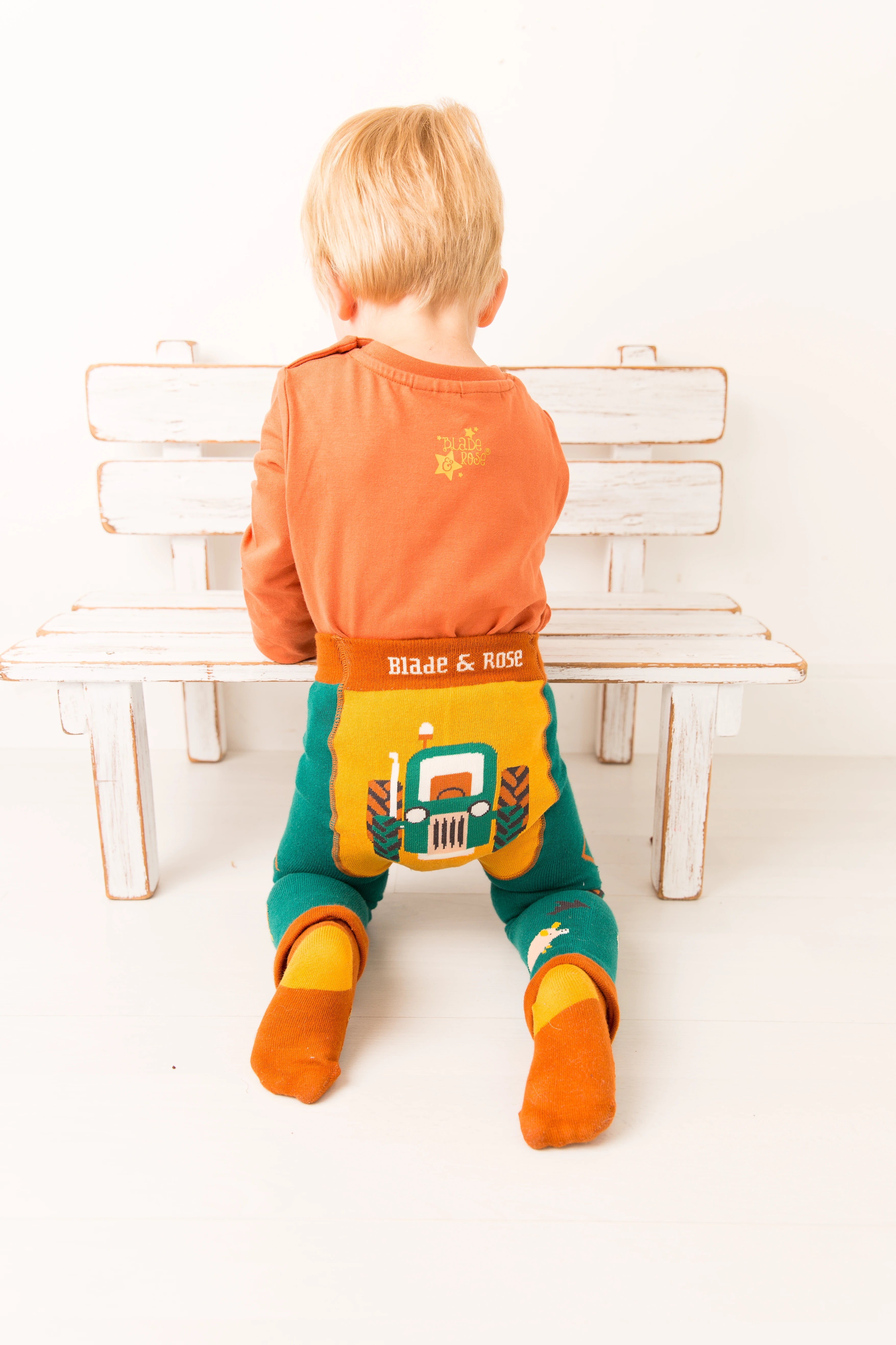 Child sitting on a bench wearing colorful clothing with visible branding.