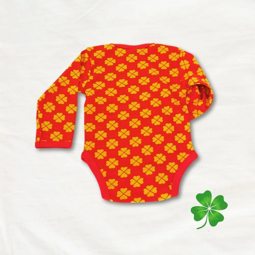 Red baby onesie with yellow pattern on a light gray background, featuring a green shamrock icon.