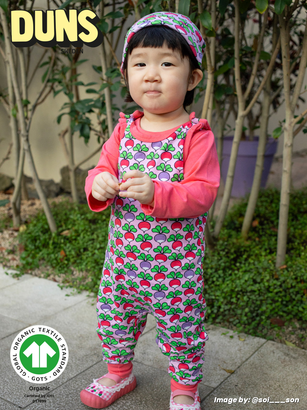 Child wearing a colorful outfit with a Duns brand logo in the corner.