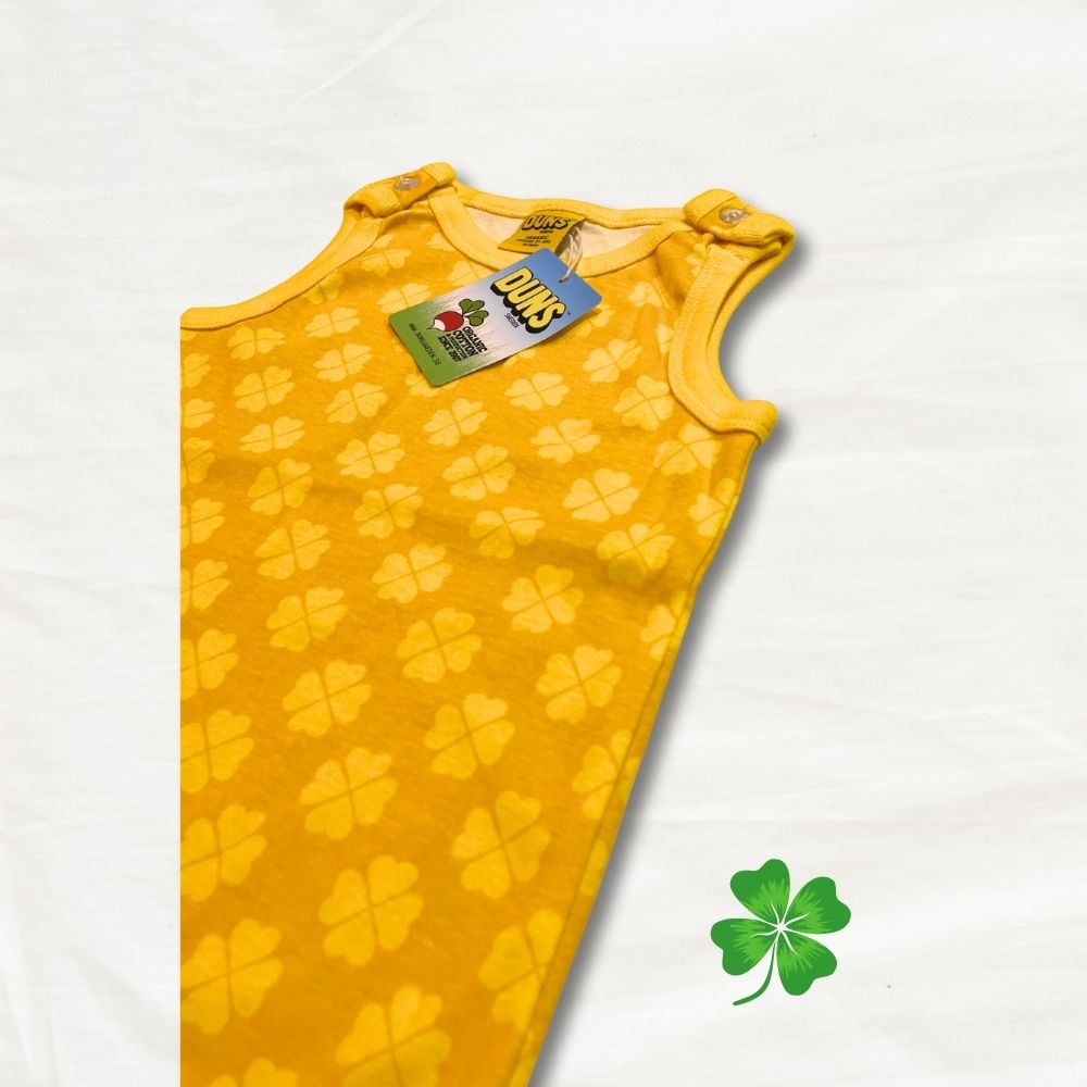 Yellow baby romper with clover pattern on a white background