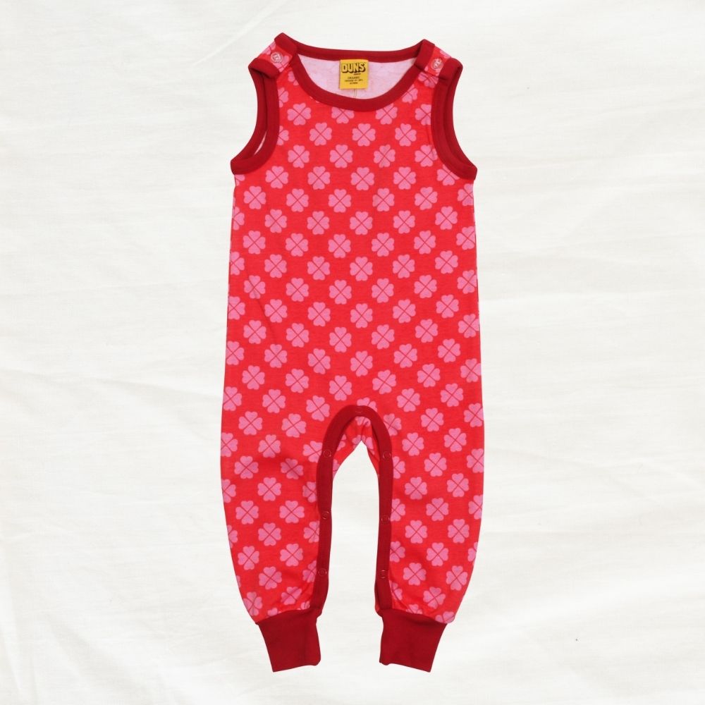 Red baby romper with clover print pattern on a white background
