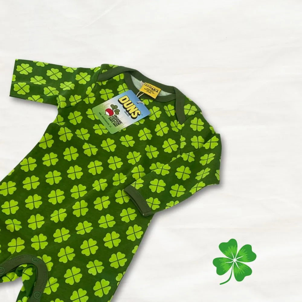 Green baby onesie with clover pattern on a white background