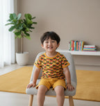 Child sitting on a chair in a room with a plant and books in the background