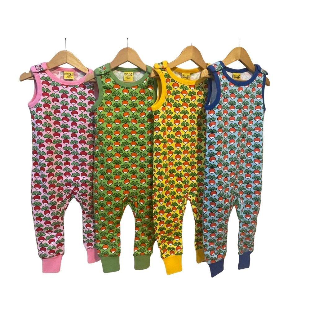Four colorful children's rompers on hangers against a white background