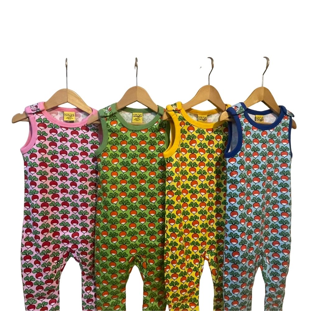 Four colorful children's rompers on hangers against a white background