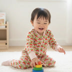 Child playing with colorful stacking toys on a light-colored floor.