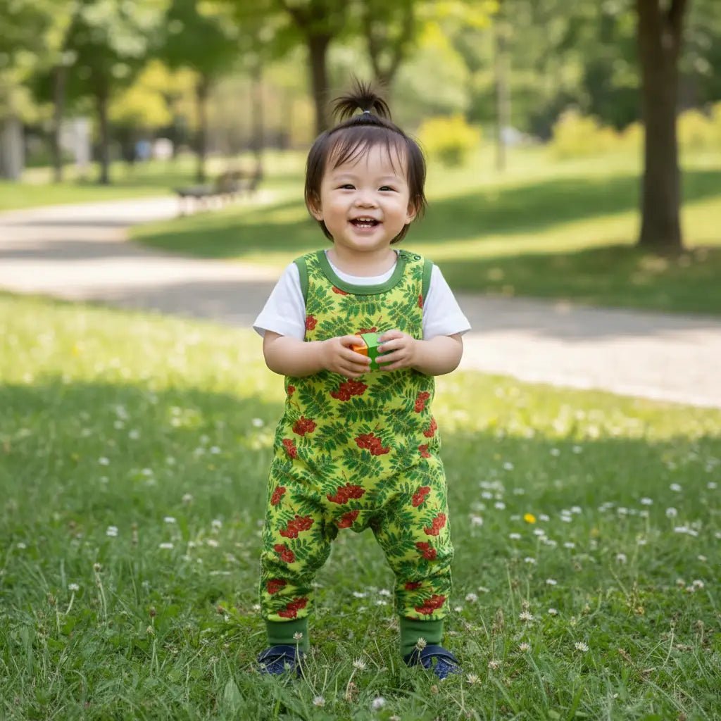 Child wearing a green floral outfit standing in a park