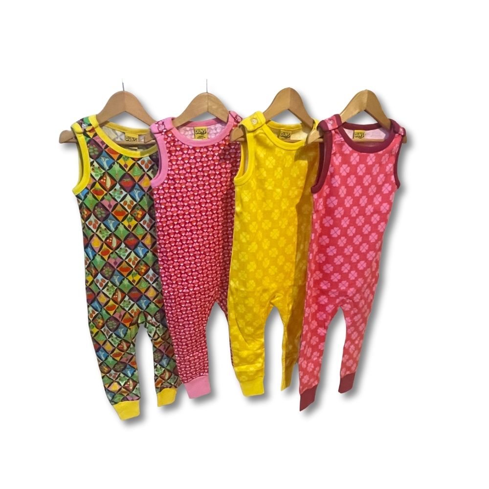Four colorful children's rompers on hangers against a white background