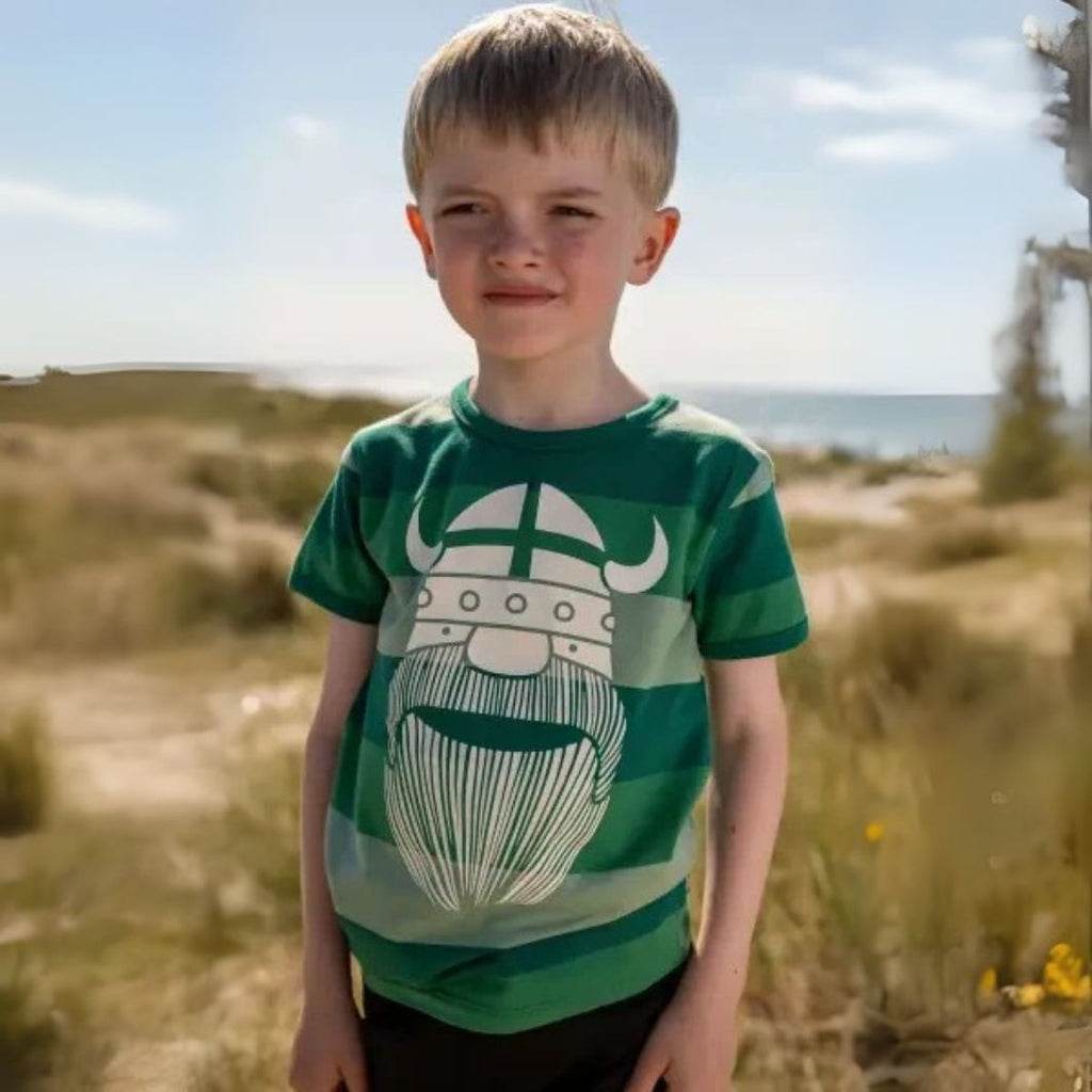 Child wearing a green t-shirt with a graphic design outdoors