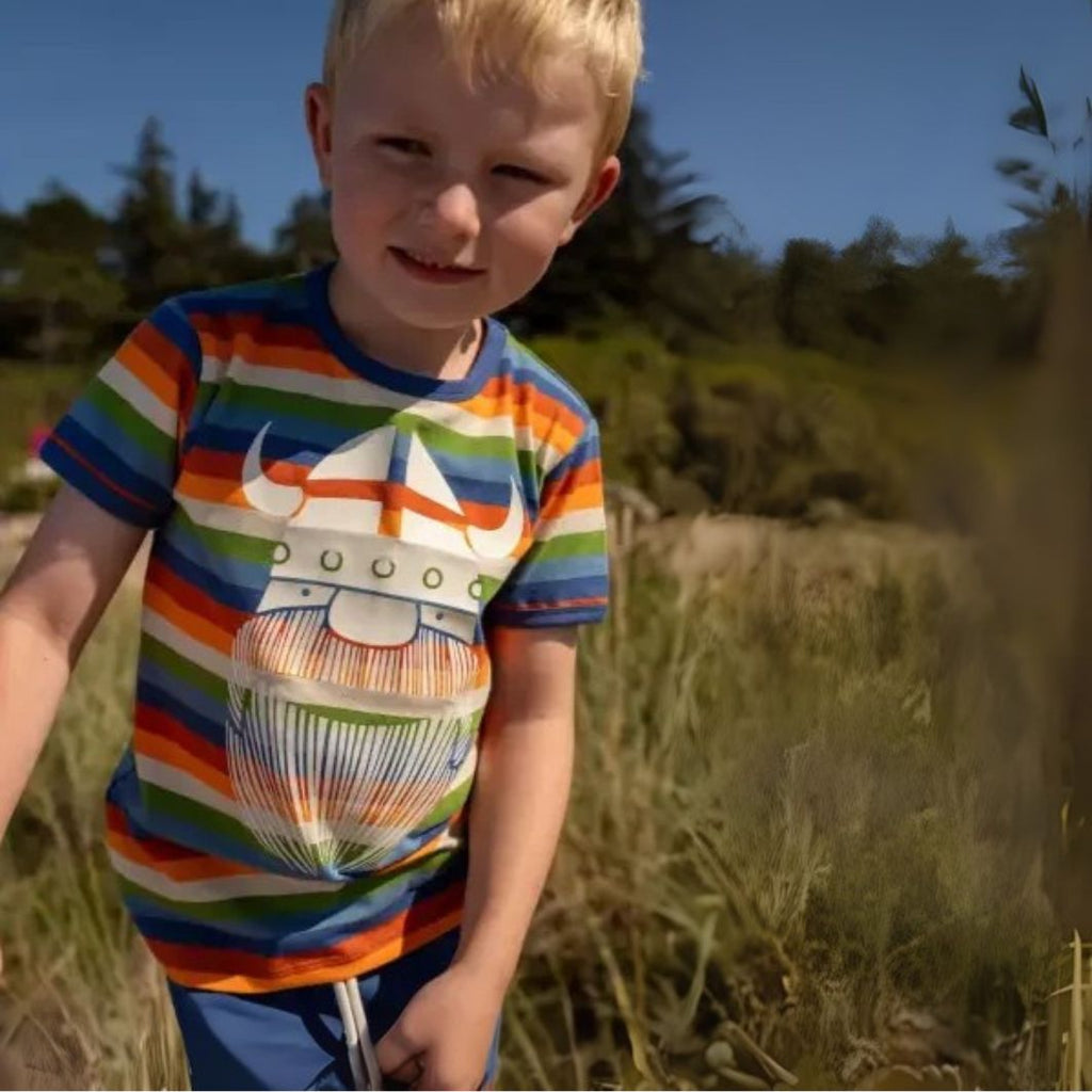 Child wearing a colorful striped shirt with a graphic design outdoors