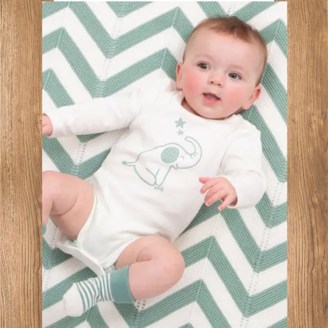 Baby lying on a green and white chevron-patterned blanket