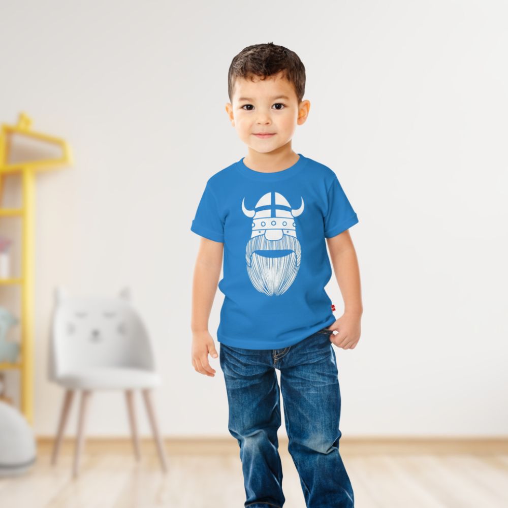 Child wearing a blue t-shirt with a Viking design in a room.