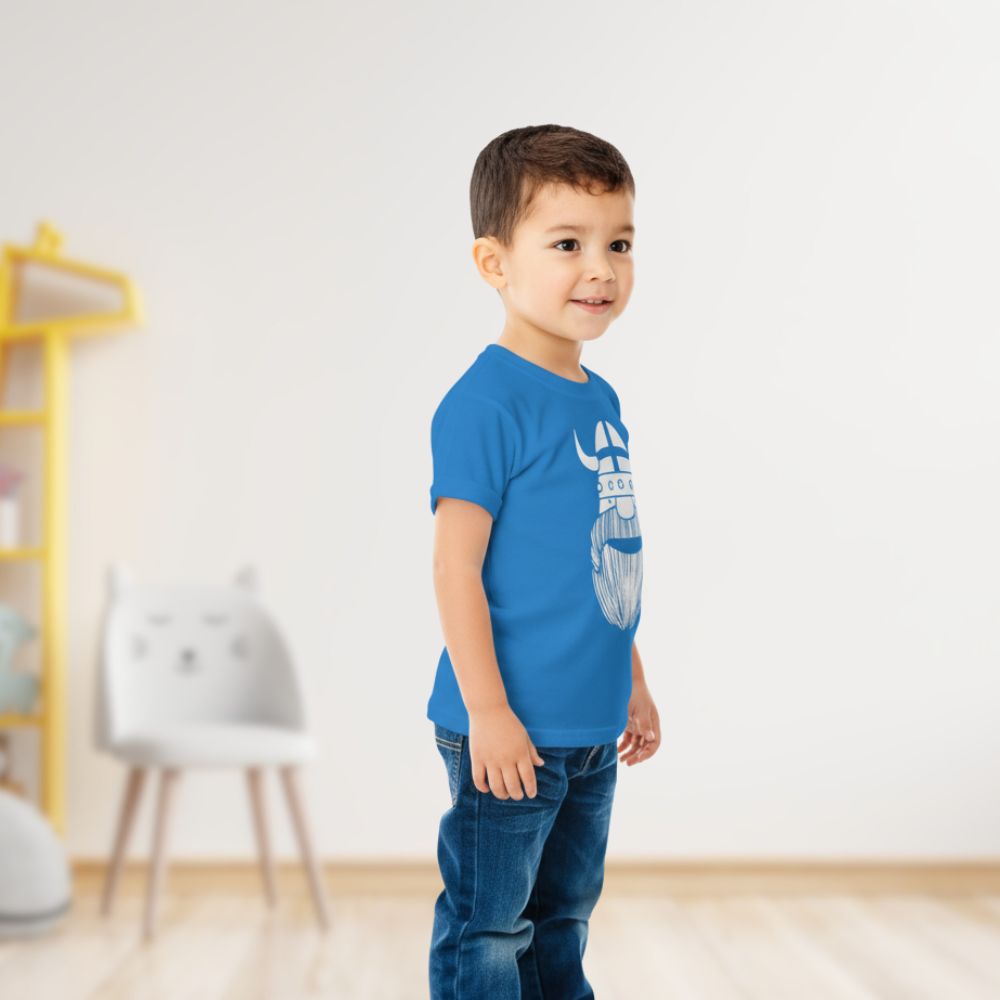 Child wearing a blue t-shirt with a graphic design in a room with a yellow shelf and white chairs.