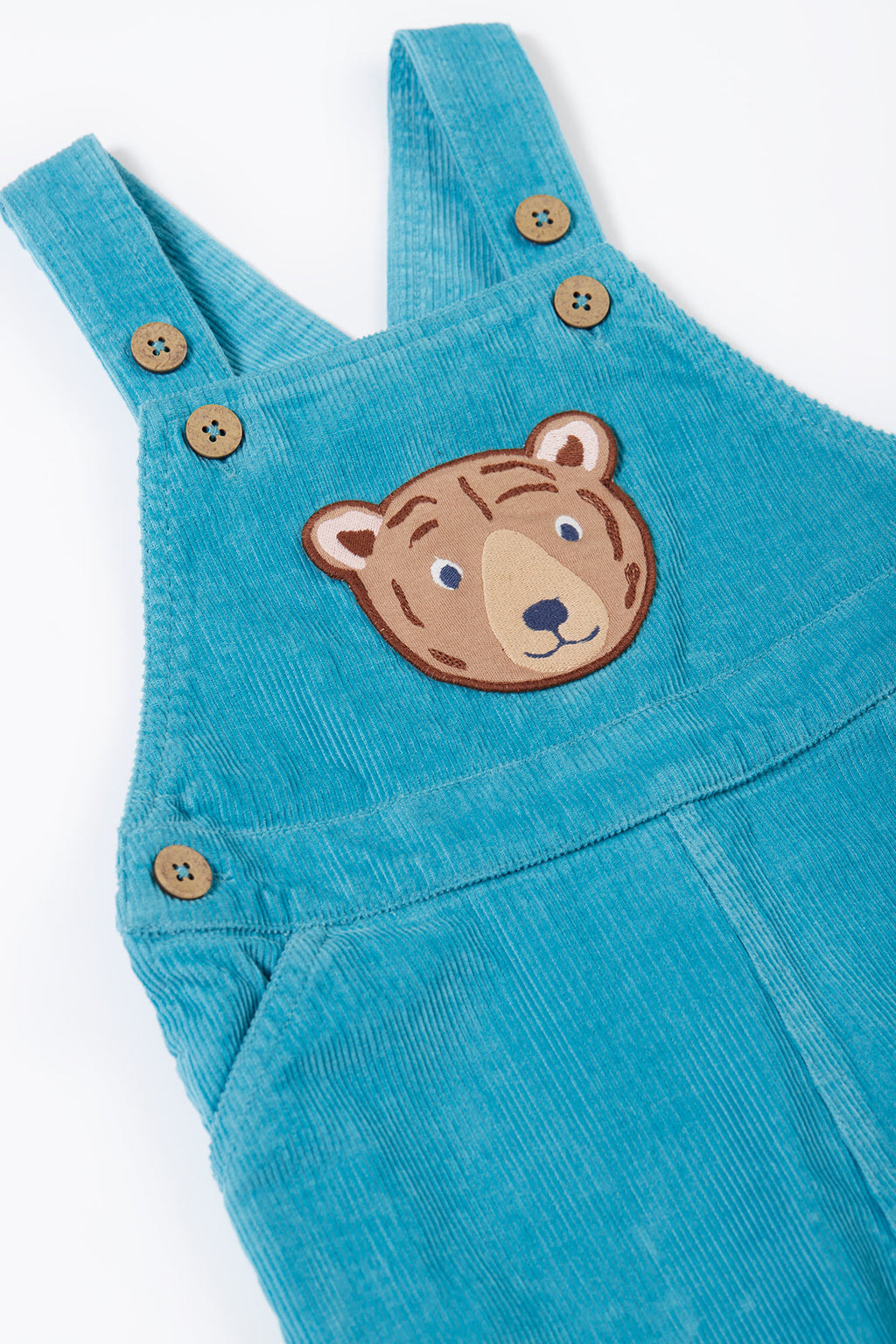 Blue corduroy overalls with a bear patch on a white background