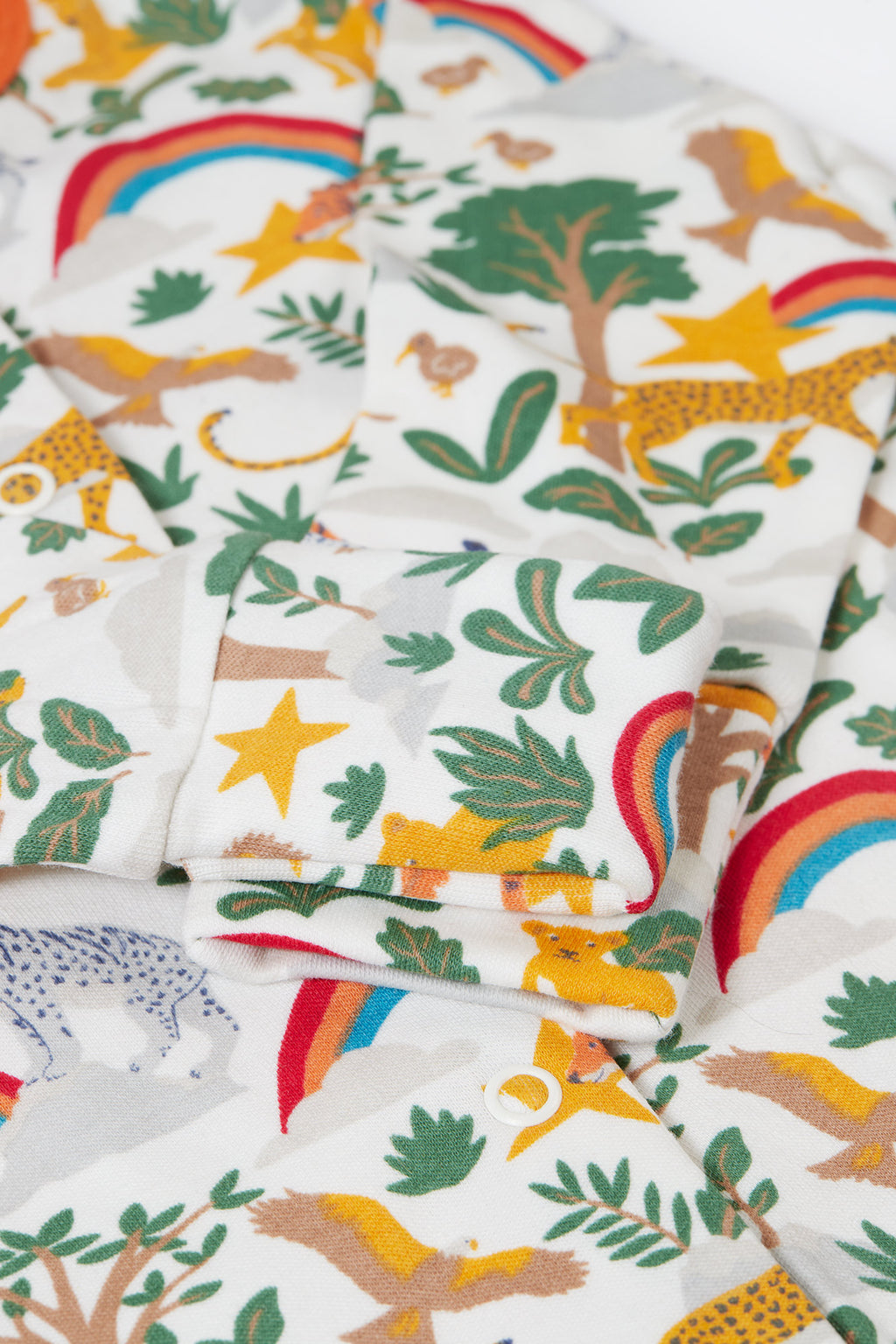 Fabric with jungle-themed pattern featuring animals, trees, and rainbows.